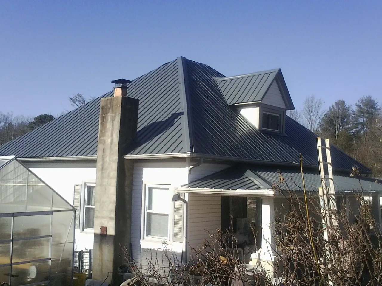 Dark blue standing seam metal roof on a white farmhouse with dormer — Slate & Tile Roof Repair by Roofing Brothers in North Highlands