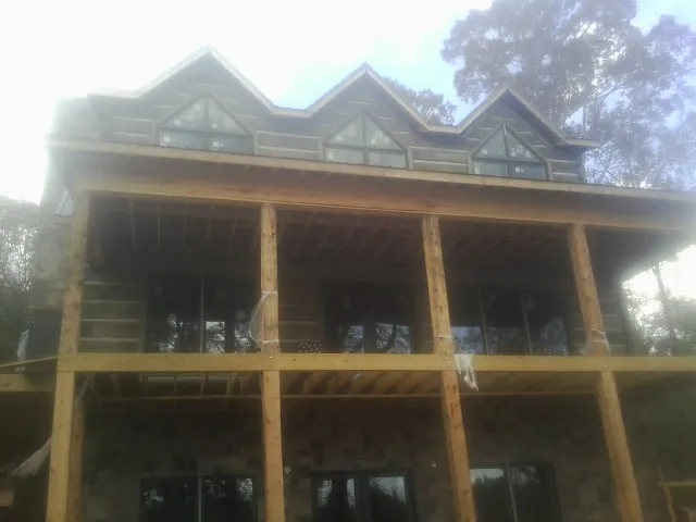 Dormers and porch framing on a large log home under construction — Roof Coating work by our crew in North Highlands