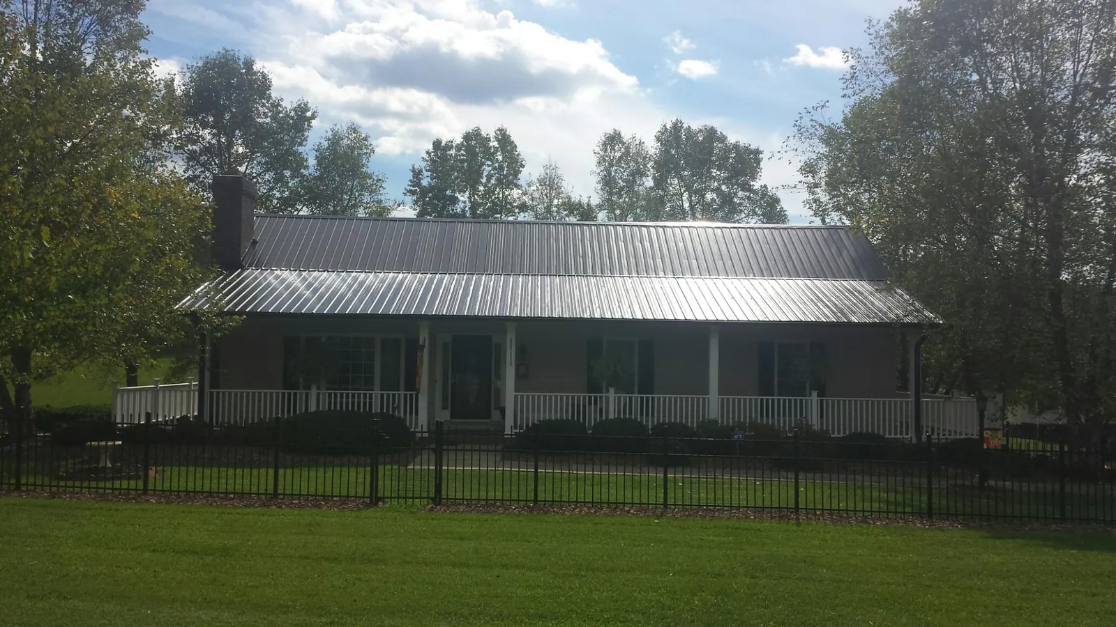 Gray metal roof on a brick ranch with a full width front porch — Gutter Guard Installation work by our crew in North Highlands