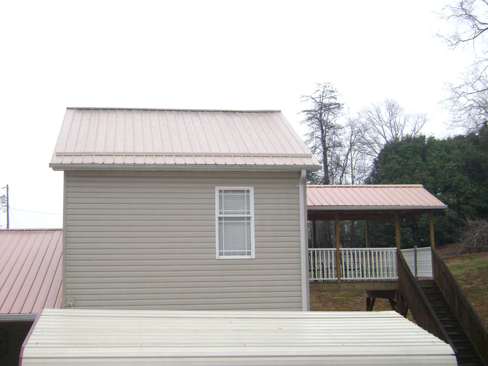 Tan metal roofs on a two story addition and attached porch, from a Roof Replacement job in North Highlands
