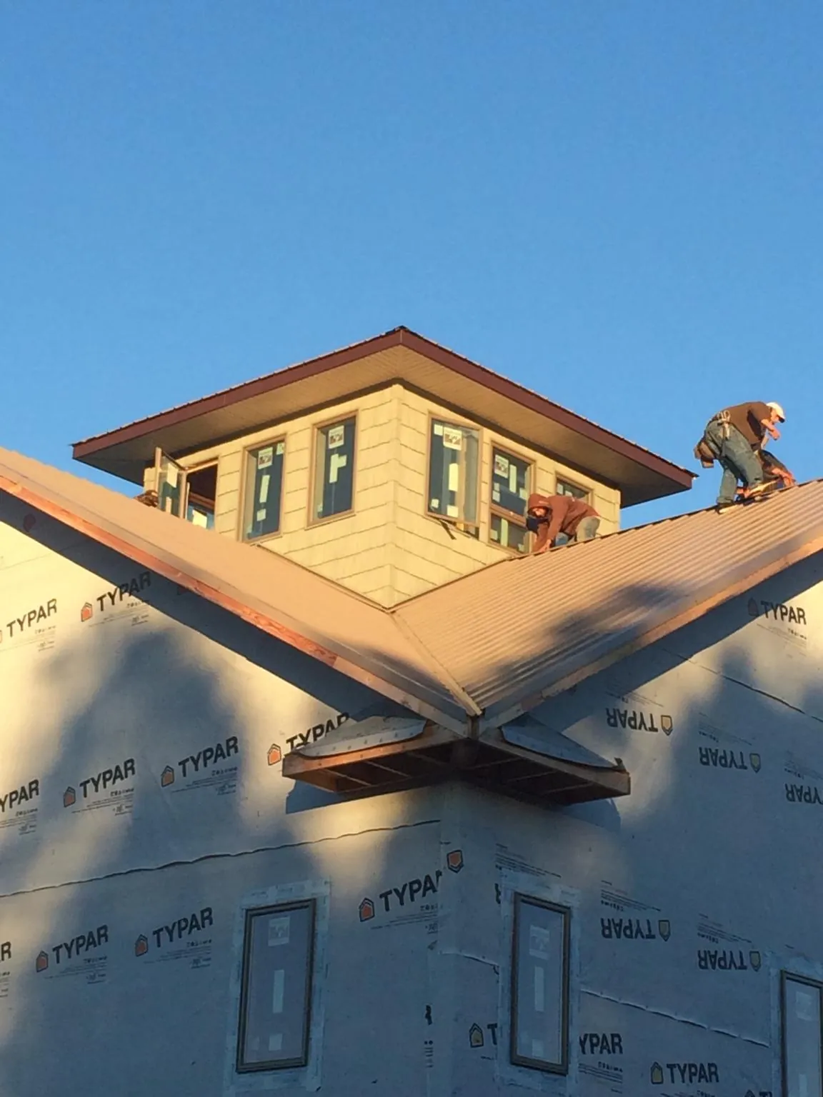 Roofers working around a rooftop cupola on a new metal roof at sunset — Roof Waterproofing in North Highlands by Roofing Brothers